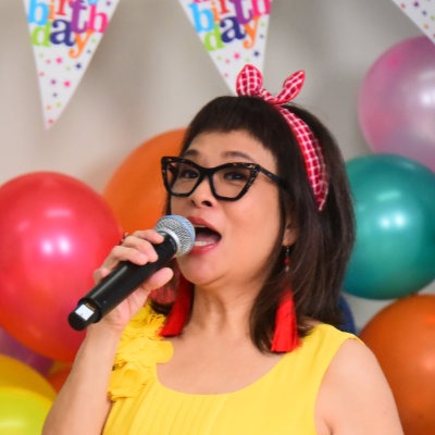 Pamela Oei wearing yellow holding a microphone hosting an Arc event